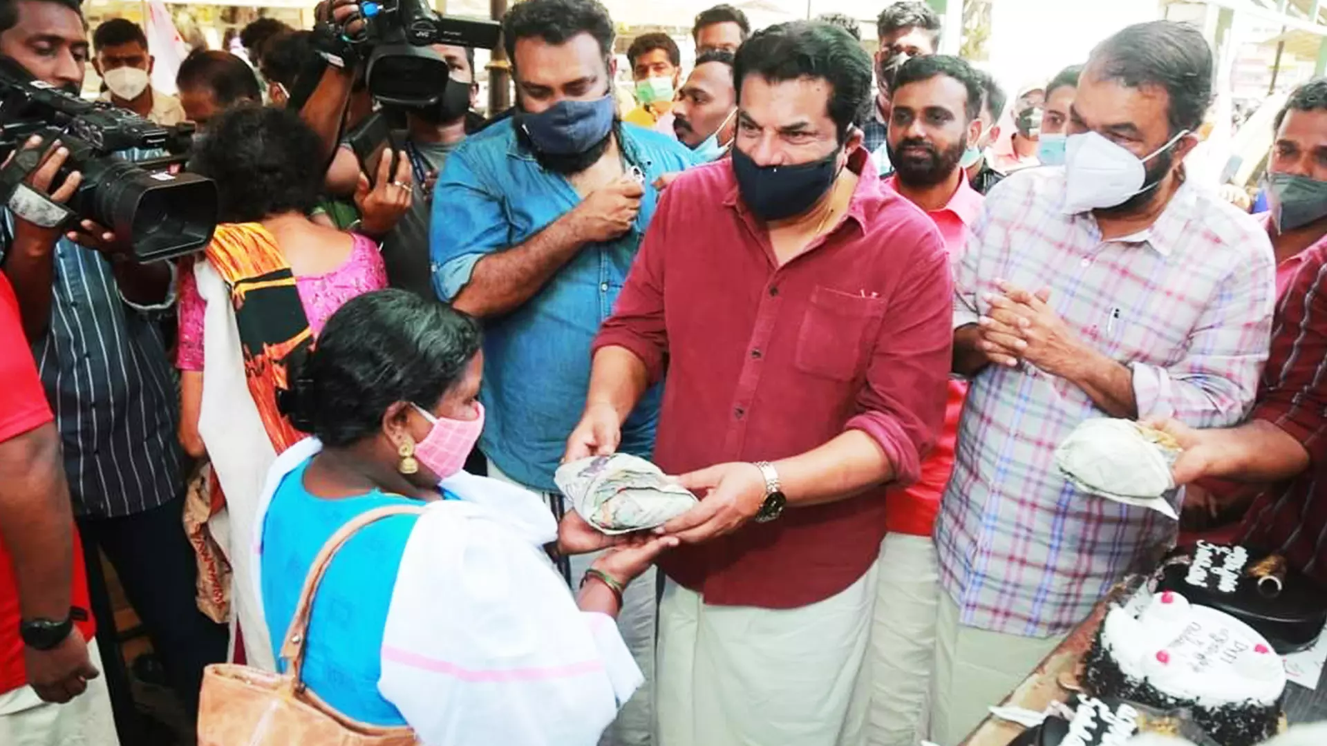 Actor-turned-legislator M Mukesh (red shirt) distributes food packets along with Kerala minister V Sivankutty.