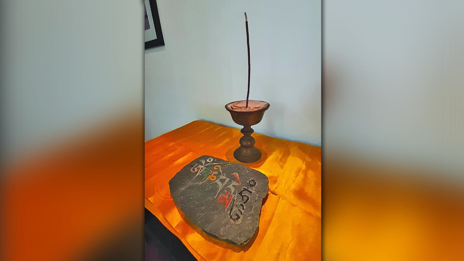 A Tibetan butter lamp with a rock slate on display with Om Mani Padme Hum (praise to the jewel in the lotus) written on it.