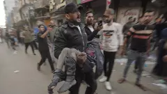 A Palestinian man runs with an injured boy following an Israeli airstrike in Khan Younis refugee camp, southern Gaza Strip, on November 18 | AP/PTI