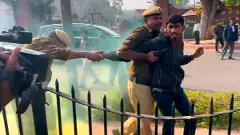 Police personnel apprehend a man carrying a can emitting yellowish smoke while he was protesting outside Parliament premises during the Winter session in New Delhi on Wednesday