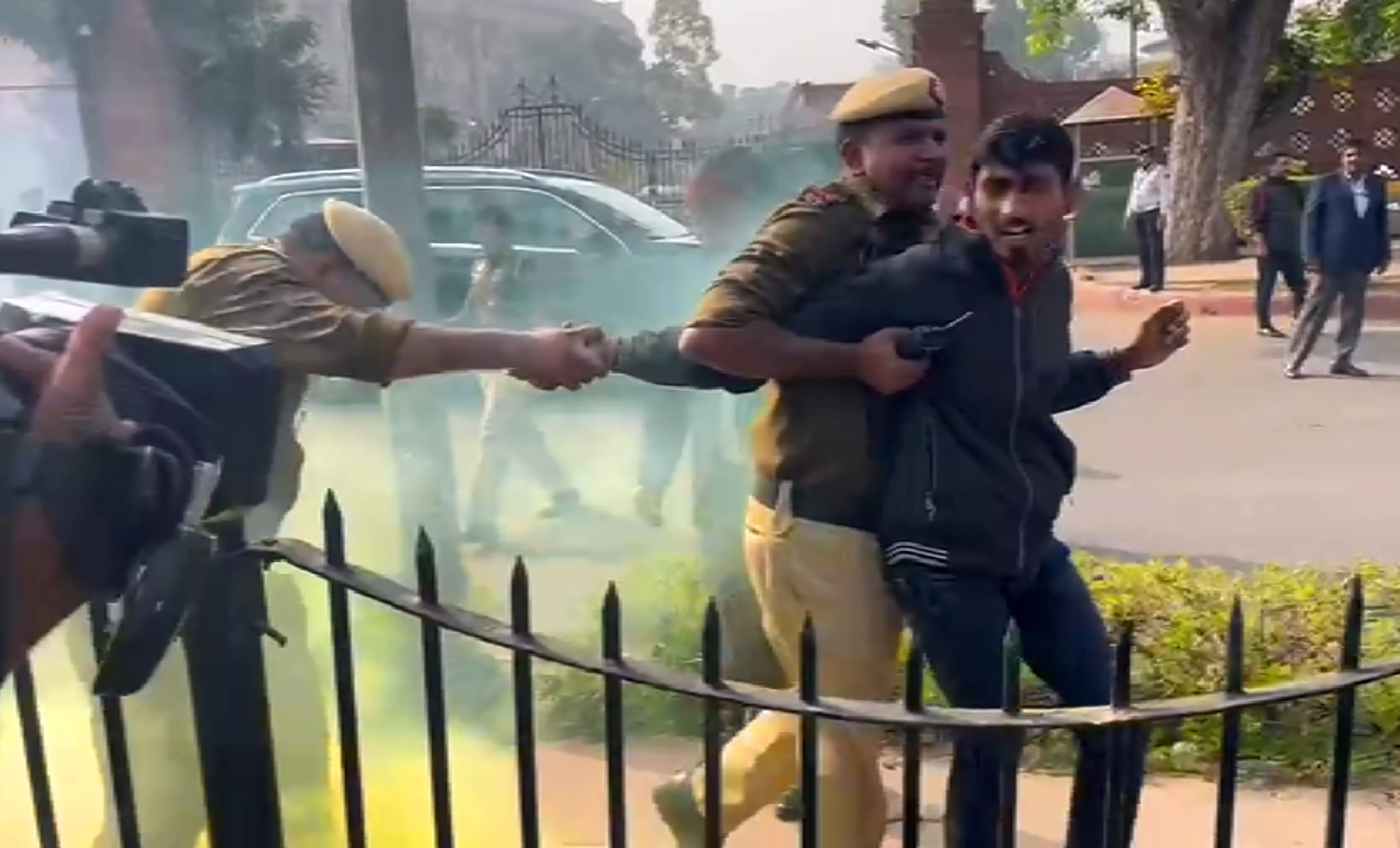Police personnel apprehend a man carrying a can emitting yellowish smoke while he was protesting outside Parliament premises during the Winter session in New Delhi on Wednesday