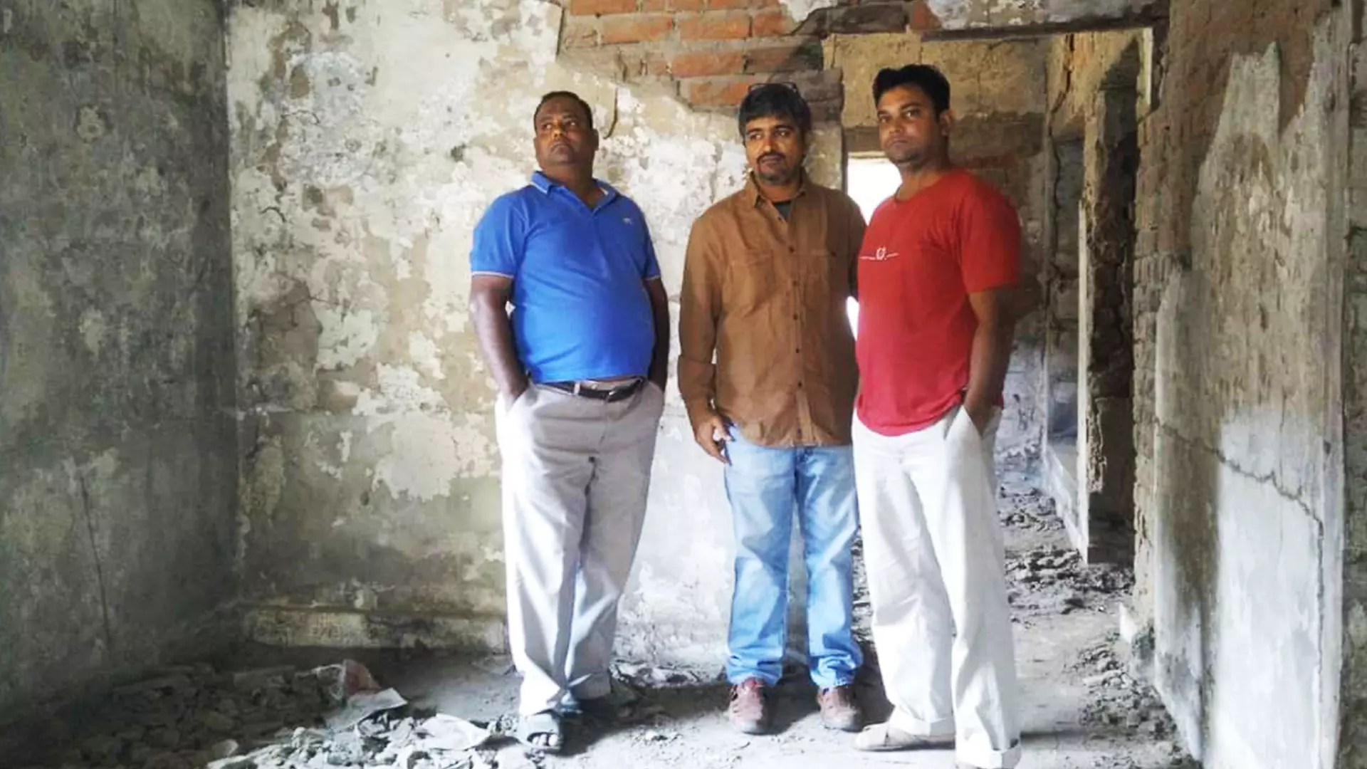 Imtiyaz (left) looking at the remains of his house.