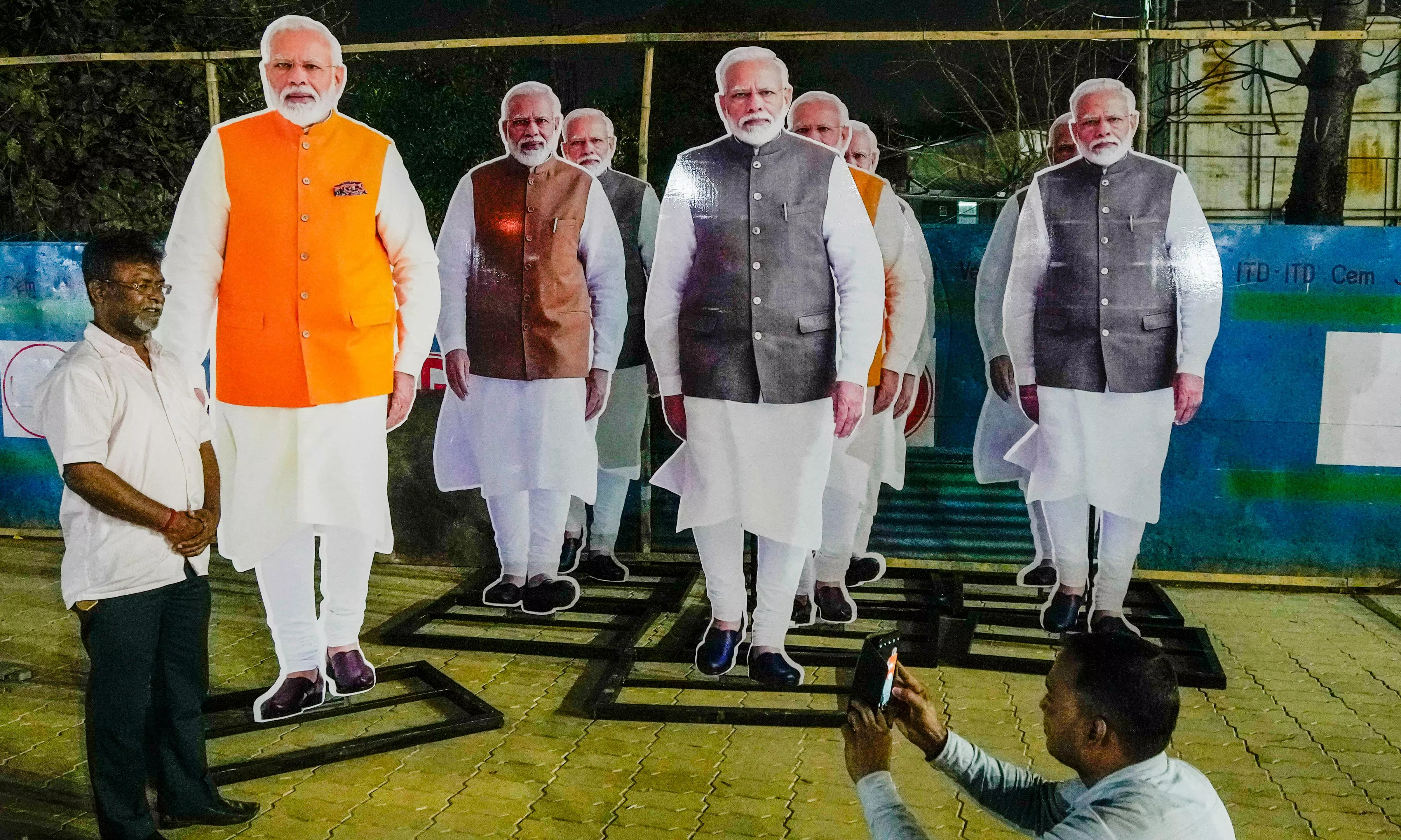 Kolkata: A worker poses for photos with cut-outs of Prime Minister Narendra Modi at Esplanade metro station, in Kolkata