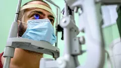 An ophthalmologist examining young mans eyesight with optical instrument.
