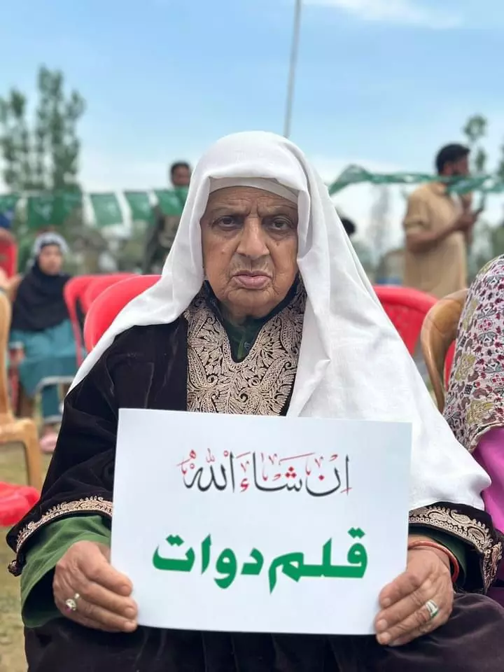 A PDP supporter holds a placard reading: In Sha Allah Qalam Dawaat, meaning God willing, pen and inkpot (PDPs party symbol). 