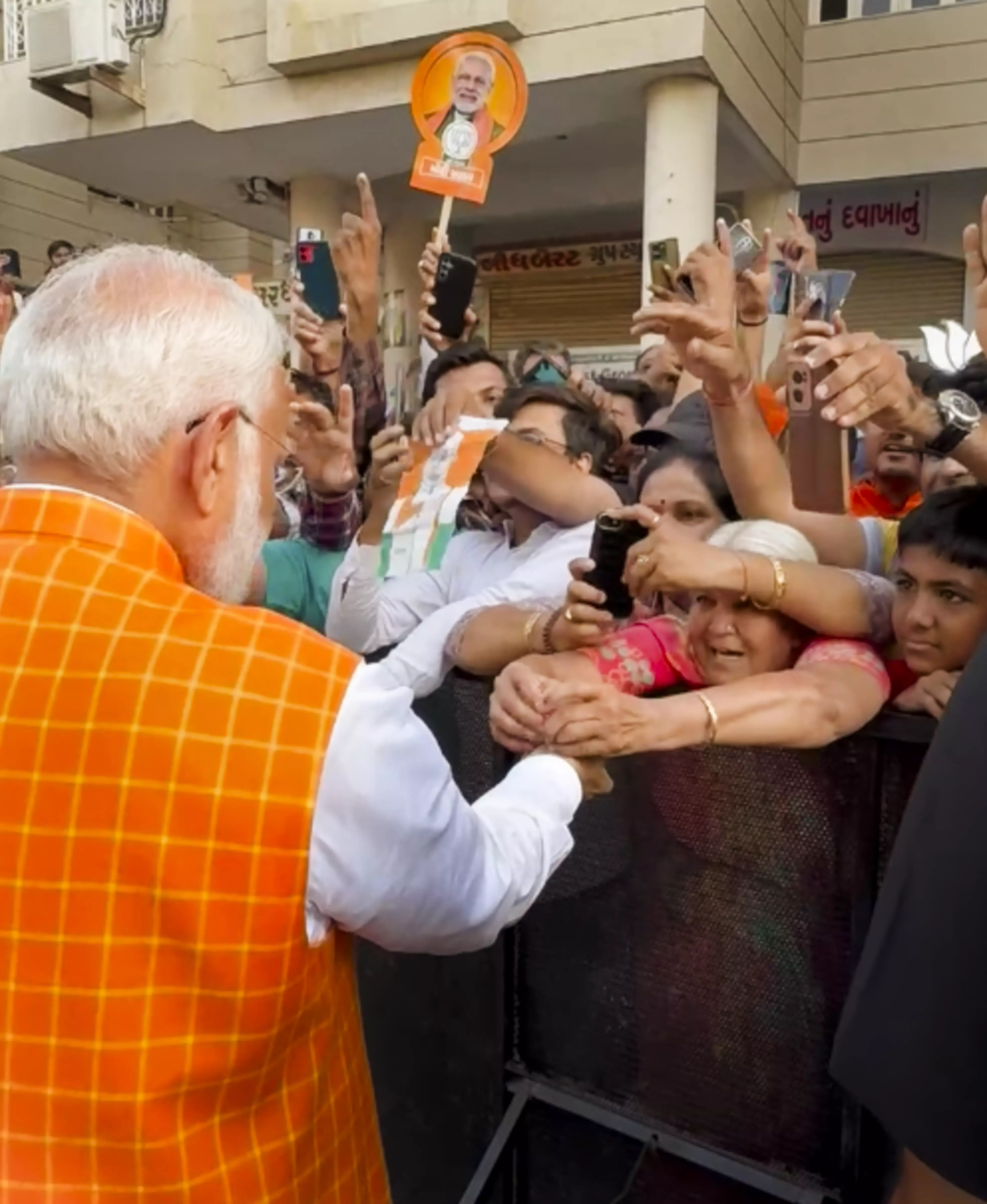 A woman ties rakhi to Prime Minister Narendra Modi as he meets people after casting his vote at a polling station during the third phase of Lok Sabha elections, in Ahmedabad. Photo: PTI