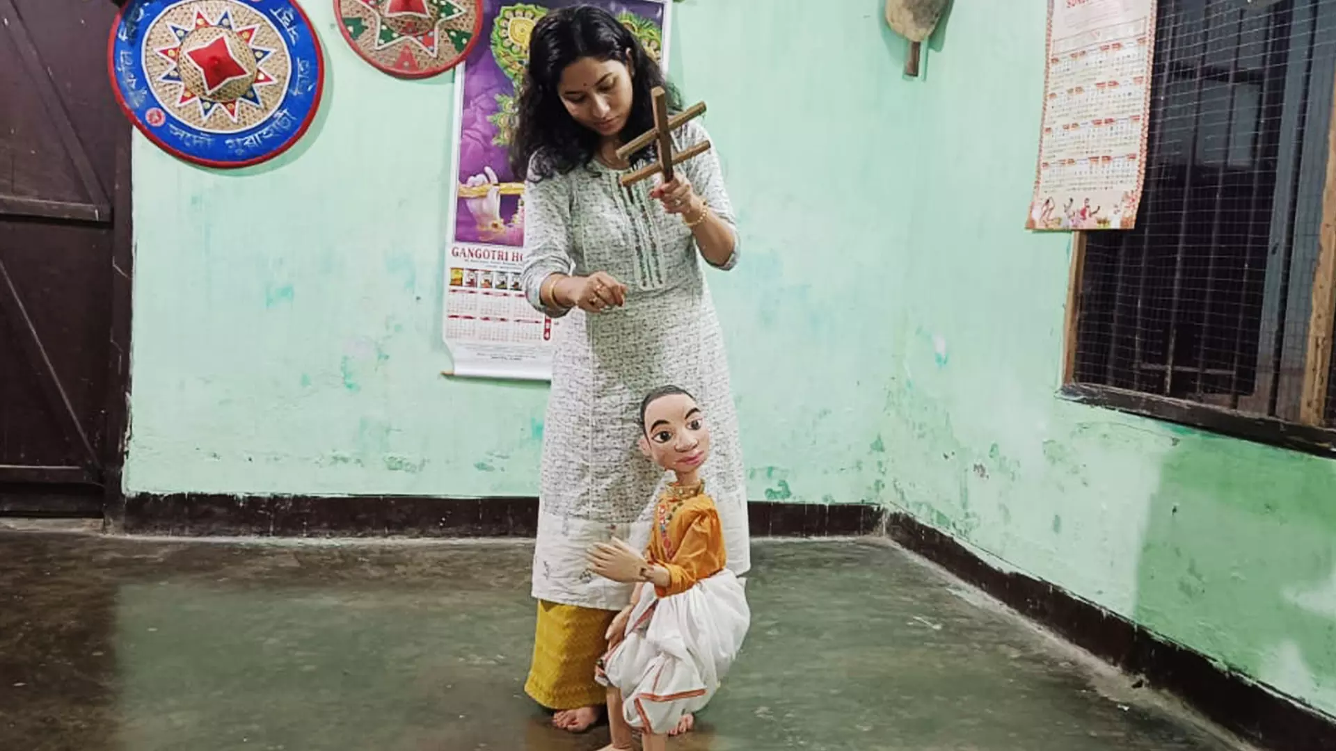 Binita Devi pulls the strings of a puppet to make it dance.