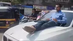 A man is lying on a car bonnet in Mumbai