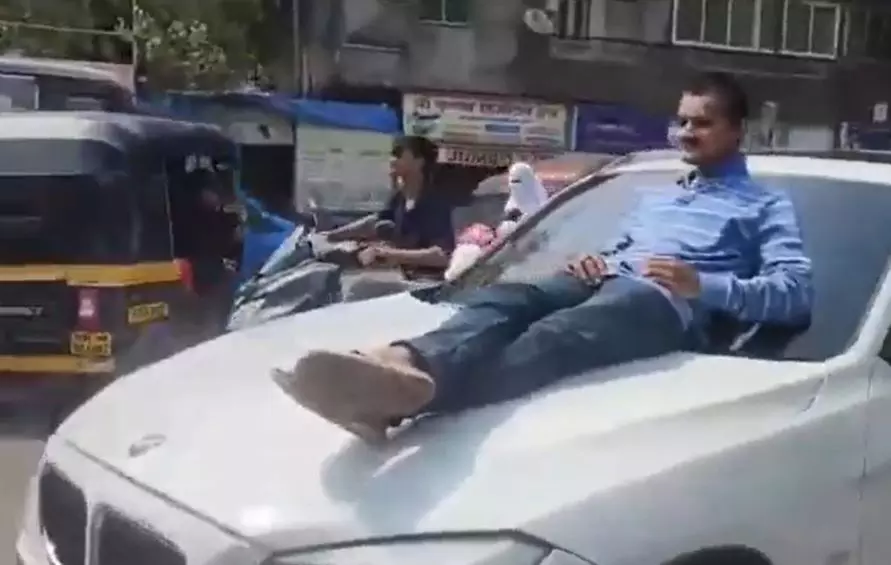 A man is lying on a car bonnet in Mumbai