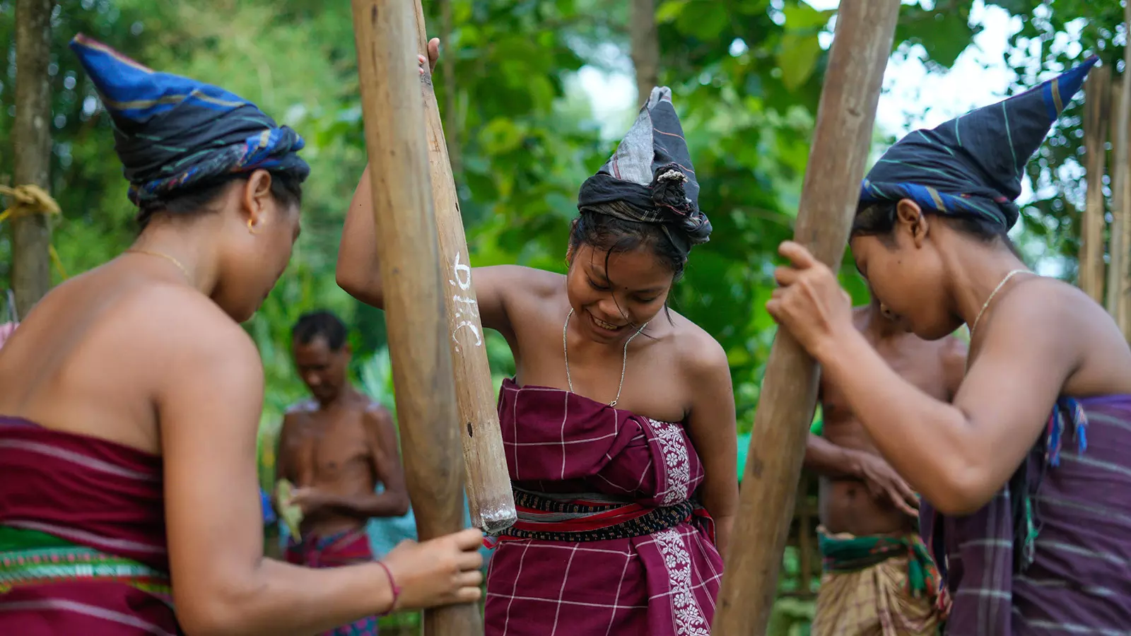 Female Baibra (priest) wearing traditional Rabha attire grind rice powder, which they will later smear on their bodies during the Baikho festival. 