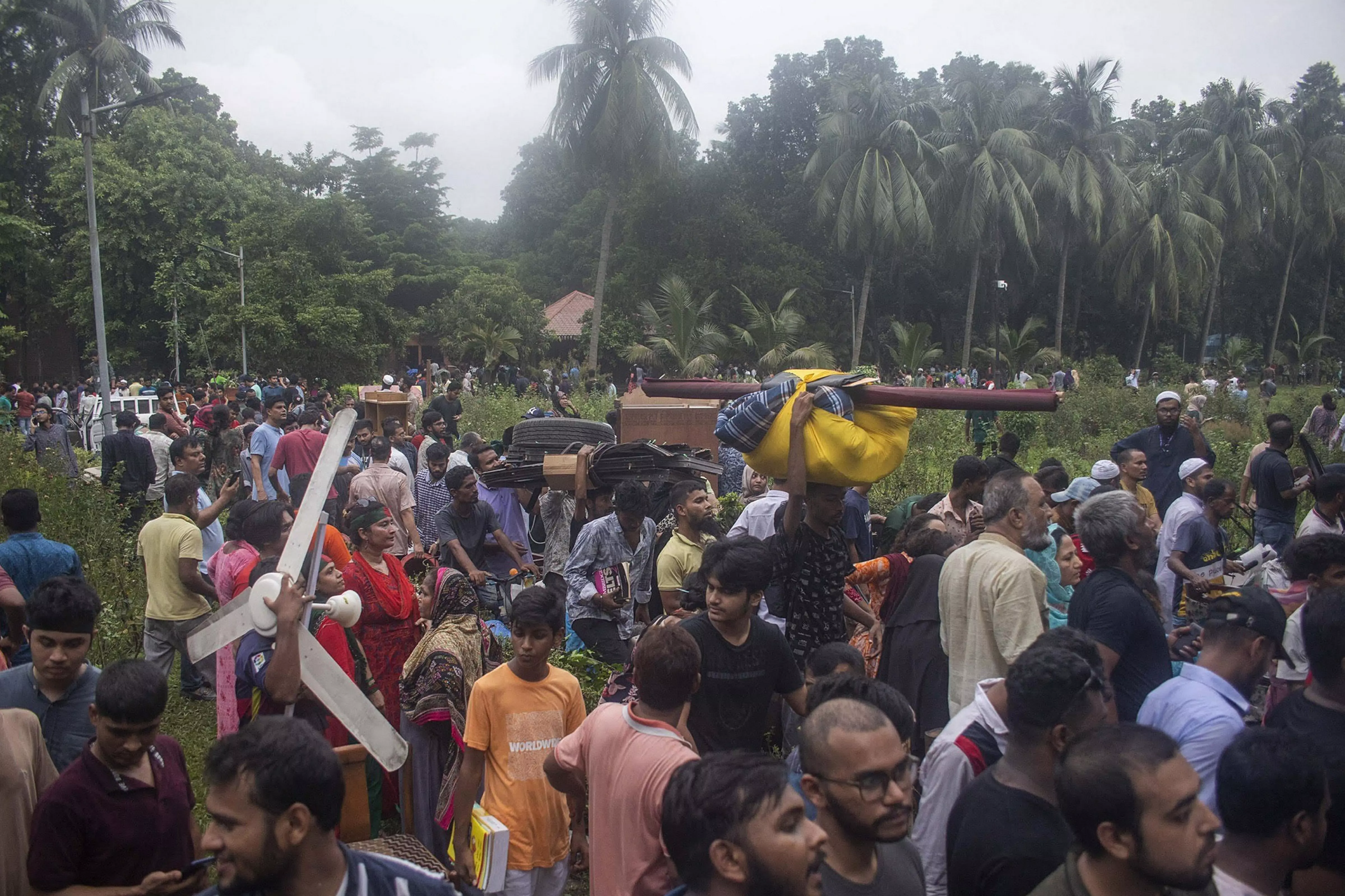 Bangladeshi people carry items from Sheikh Hasinas house in Dhaka on Monday. | EPA-EFE via PTI