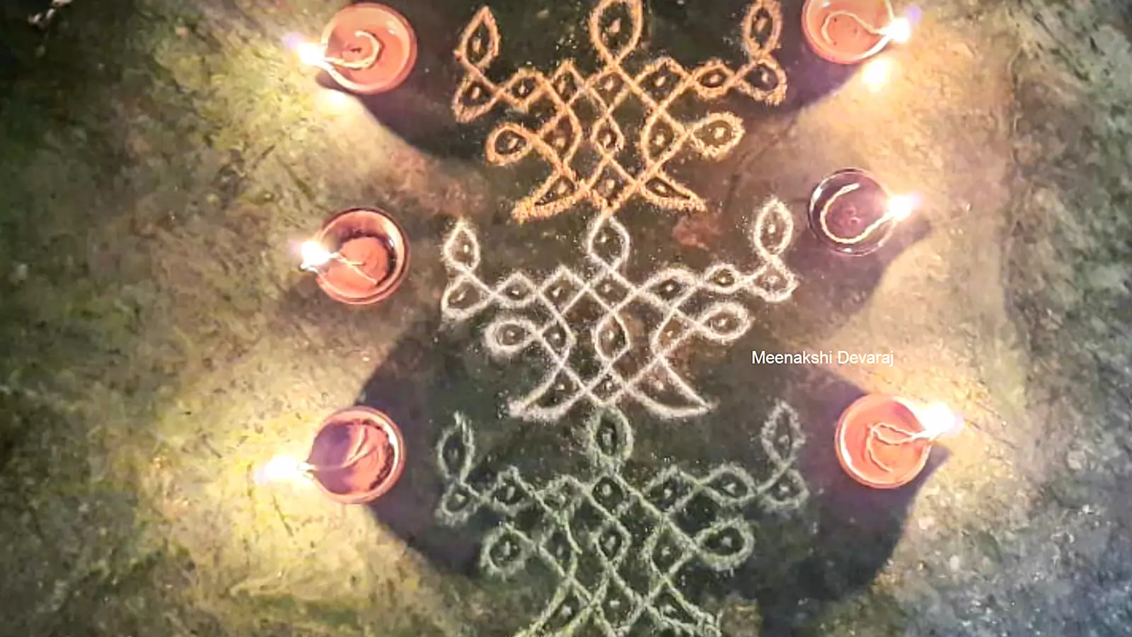 A kolam adorned with traditional diyas.