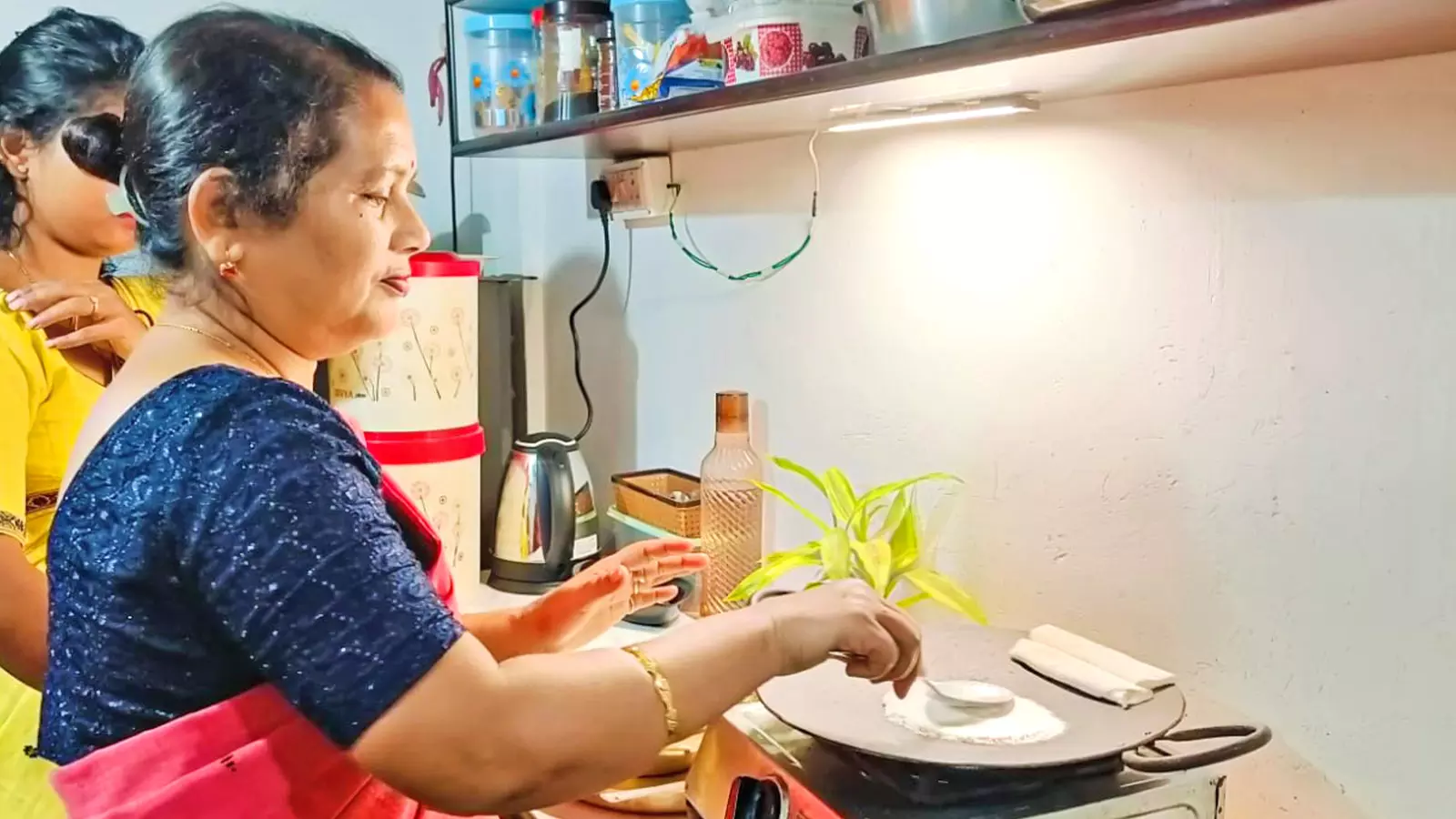 Alaka Devi Chakravarty prepares narikol (coconut-stuffed) pitha on a hot griddle.