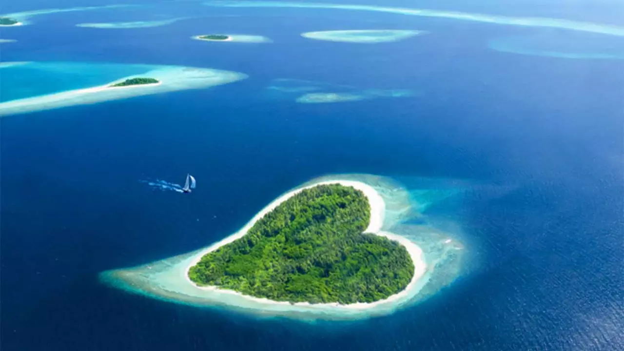 A picture of a heart-shaped island covered in forest cover in a vast blue sea with a few islands around it at a distance A picture of a heart-shaped island covered in forest cover in a vast blue sea with a few islands around it at a distance