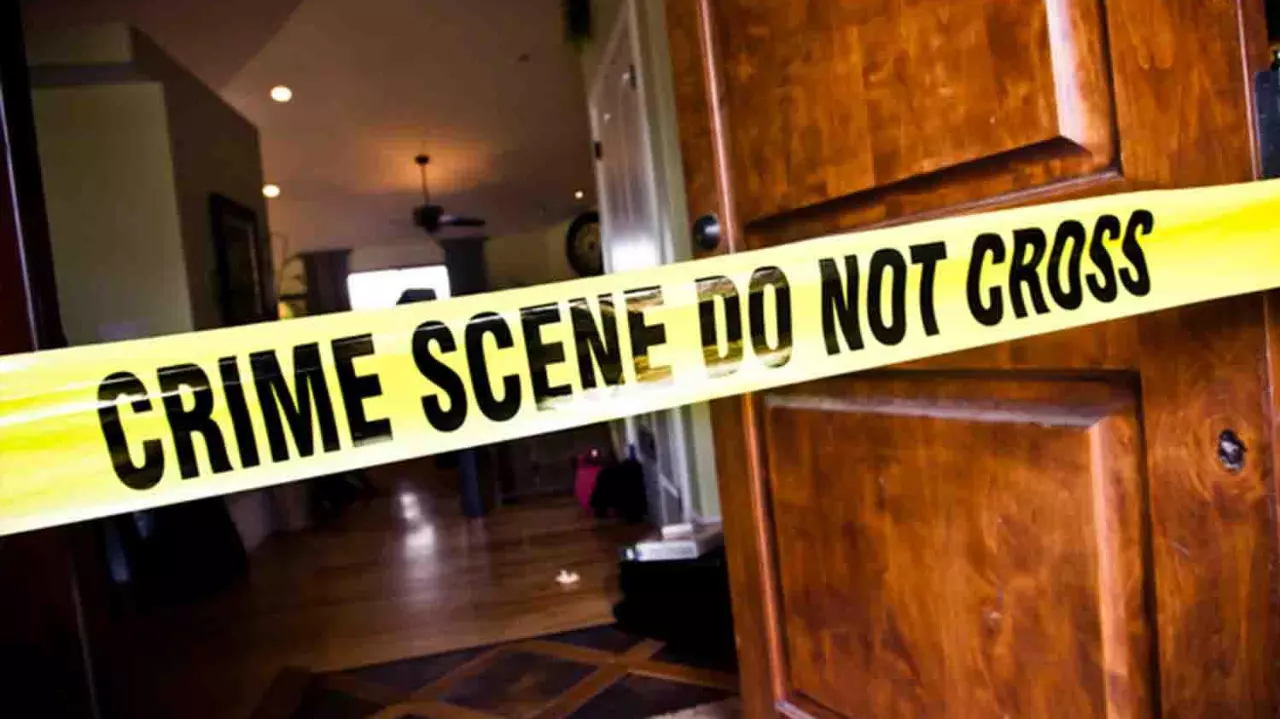 Yellow crime scene do not cross police tape over the entrance of a house with the front door wide open