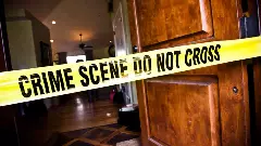 Yellow crime scene do not cross police tape over the entrance of a house with the front door wide open
