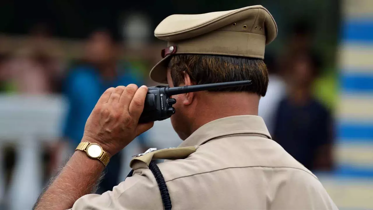 A picture of an IPS officer from the back listening to a walkie talkie