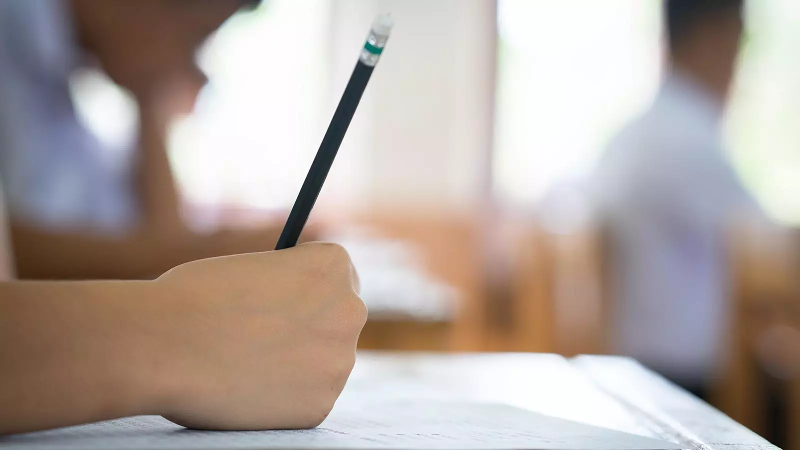 A closeup of a student writing with a pencil.