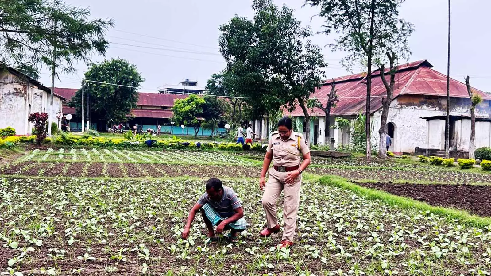 As an inmate tends to the vegetable garden, Nayama Ahmed supervises him.