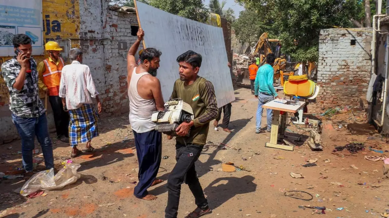 People carry their belongings during a demolition drive by the Amdavad Municipal Corporation near the Chandola lake, in Ahmedabad, last week. Image: PTI