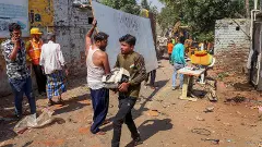 People carry their belongings during a demolition drive by the Amdavad Municipal Corporation near the Chandola lake, in Ahmedabad, last week. Image: PTI