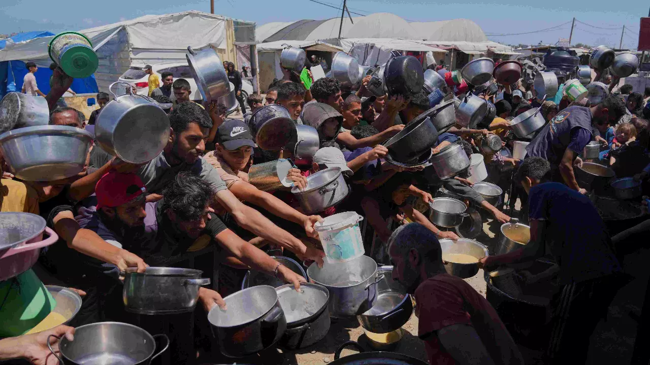 Palestinians struggle to get donated food at a community kitchen in Khan Younis