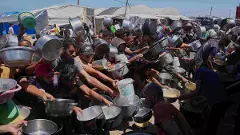 Palestinians struggle to get donated food at a community kitchen in Khan Younis