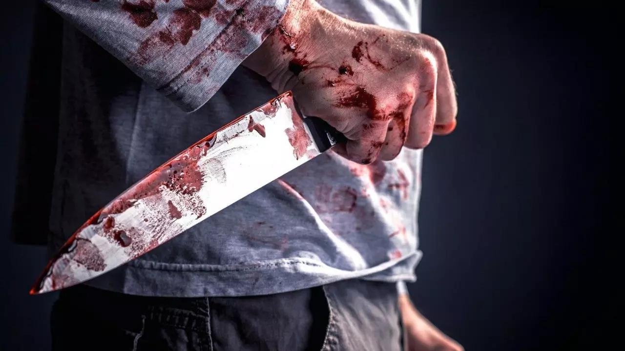 Midsection Of Murderer Holding Blooded Knife Against Black Background