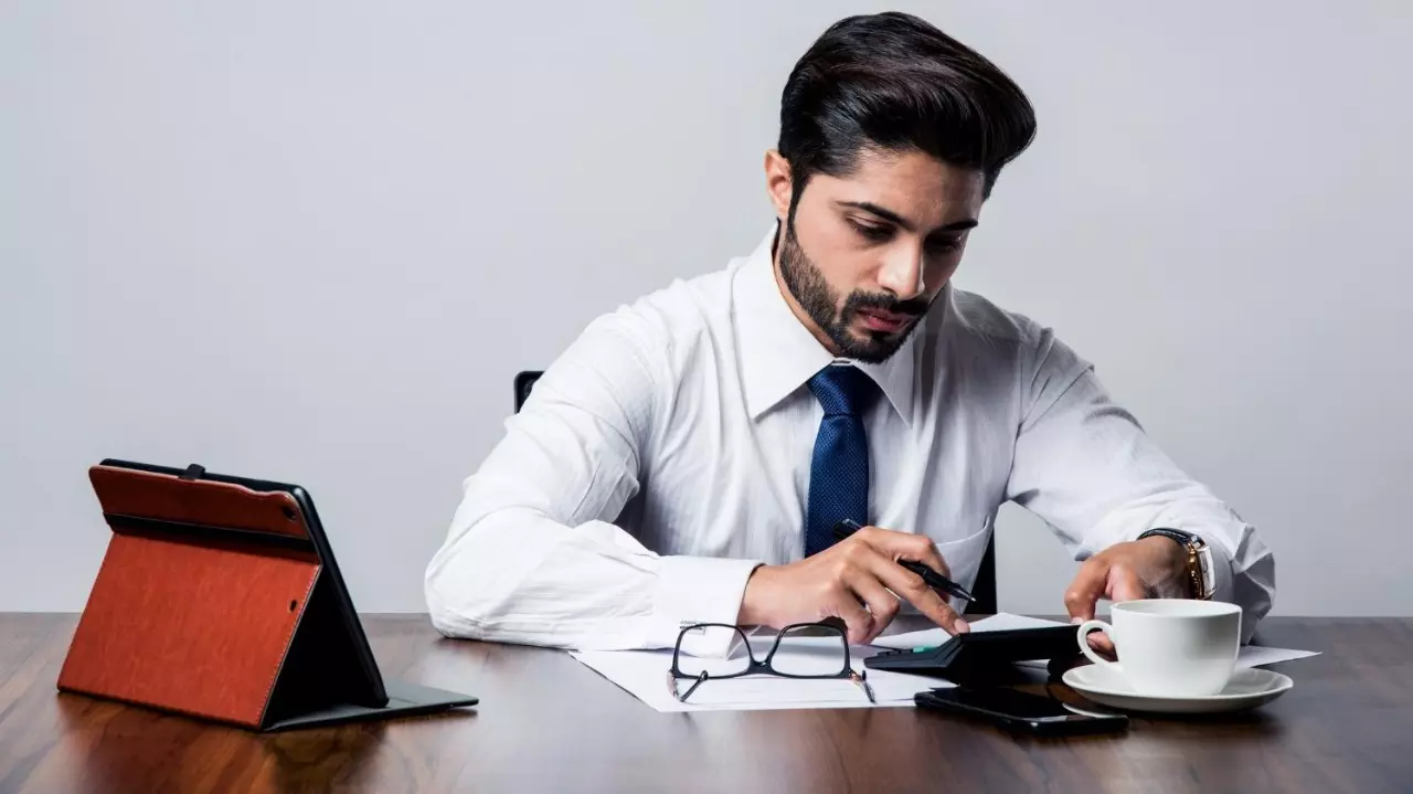 Bearded Indian Businessman accounting while sitting at desk Bearded Indian Businessman accounting while sitting at desk