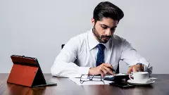 Bearded Indian Businessman accounting while sitting at desk