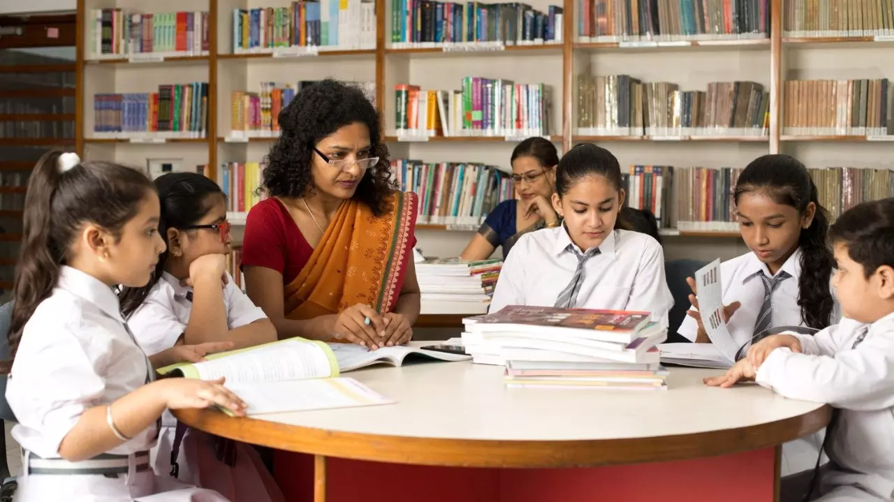 Female teachers teaching students in library at school