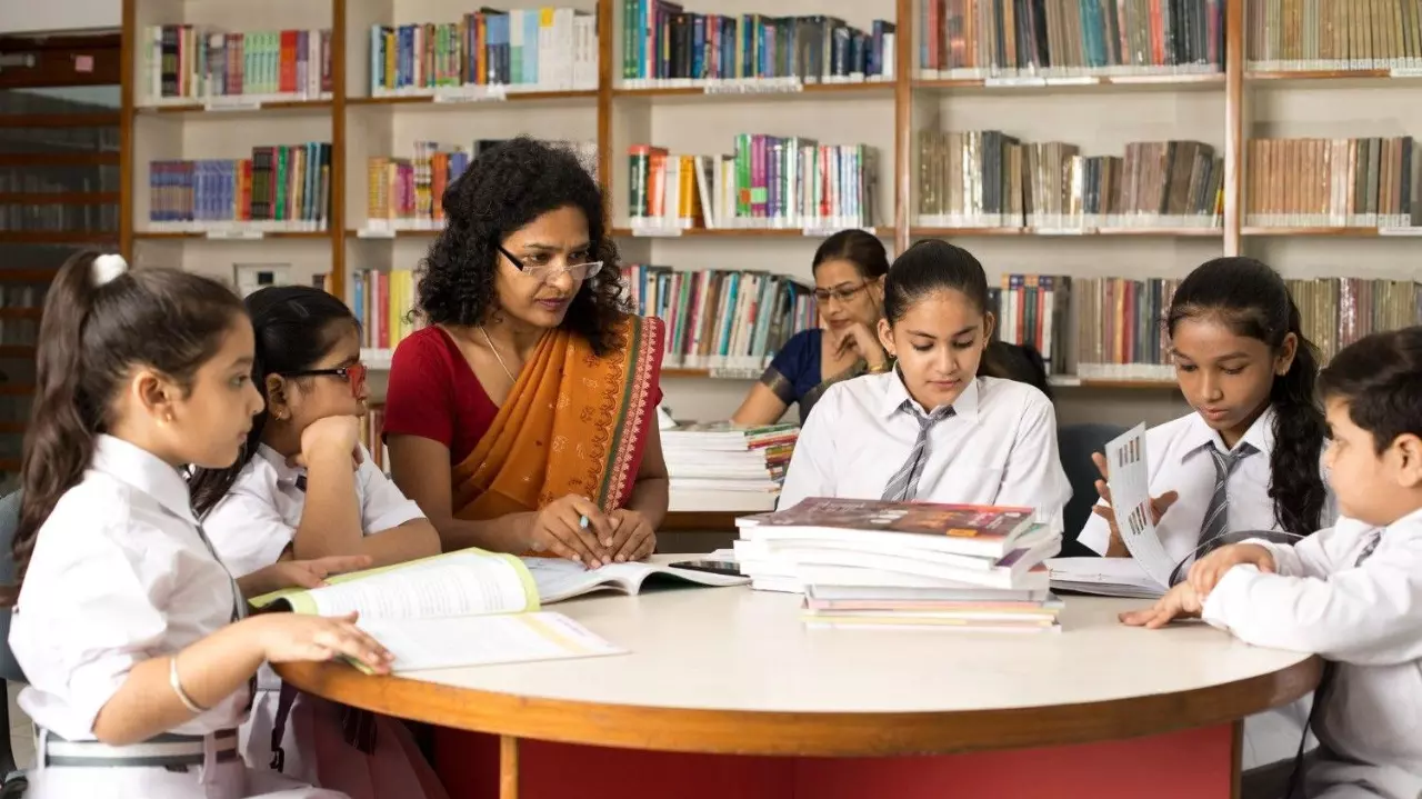 Female teachers teaching students in library at school