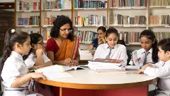 Female teachers teaching students in library at school