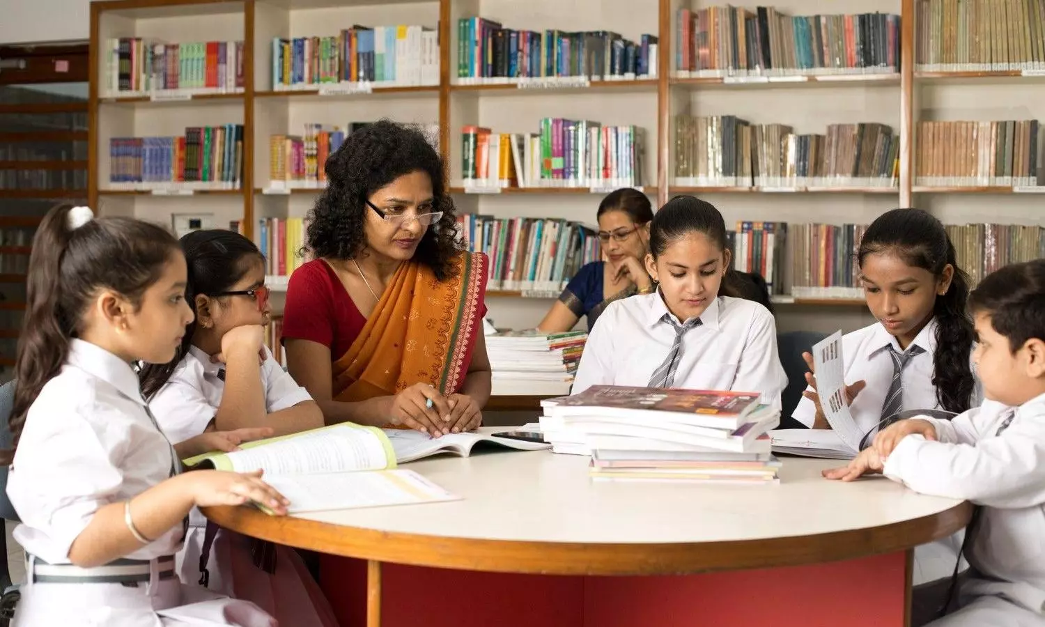 Female teachers teaching students in library at school Female teachers teaching students in library at school