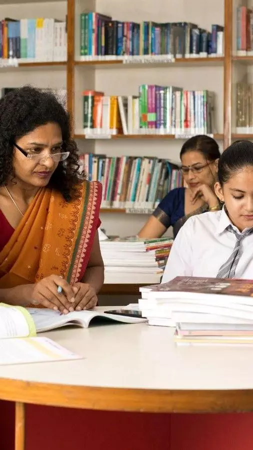 Female teachers teaching students in library at school Female teachers teaching students in library at school