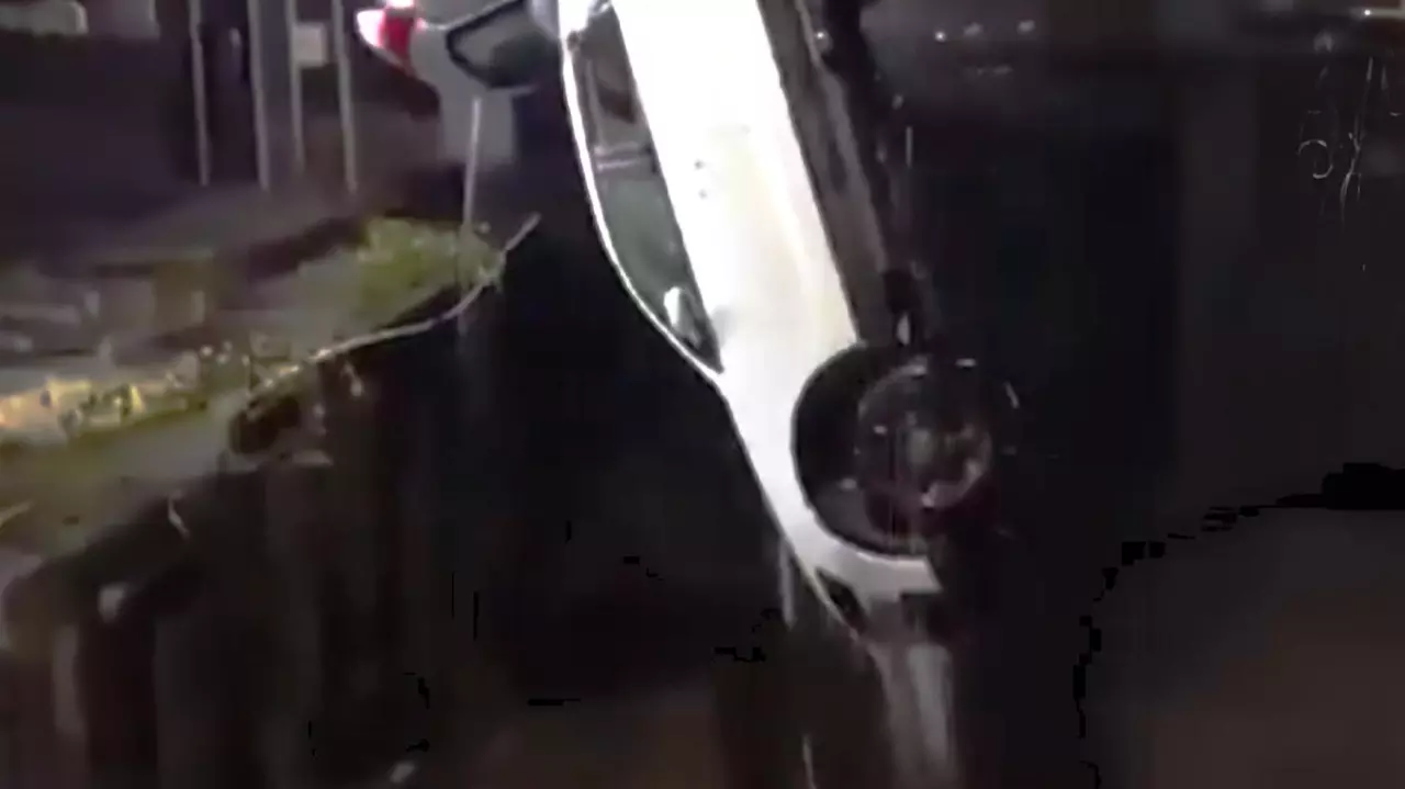 A white hatchback retrieved from the ditch using a crane