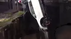 A white hatchback retrieved from the ditch using a crane