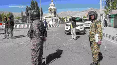 Security personnel stand guard on a road amid curfew