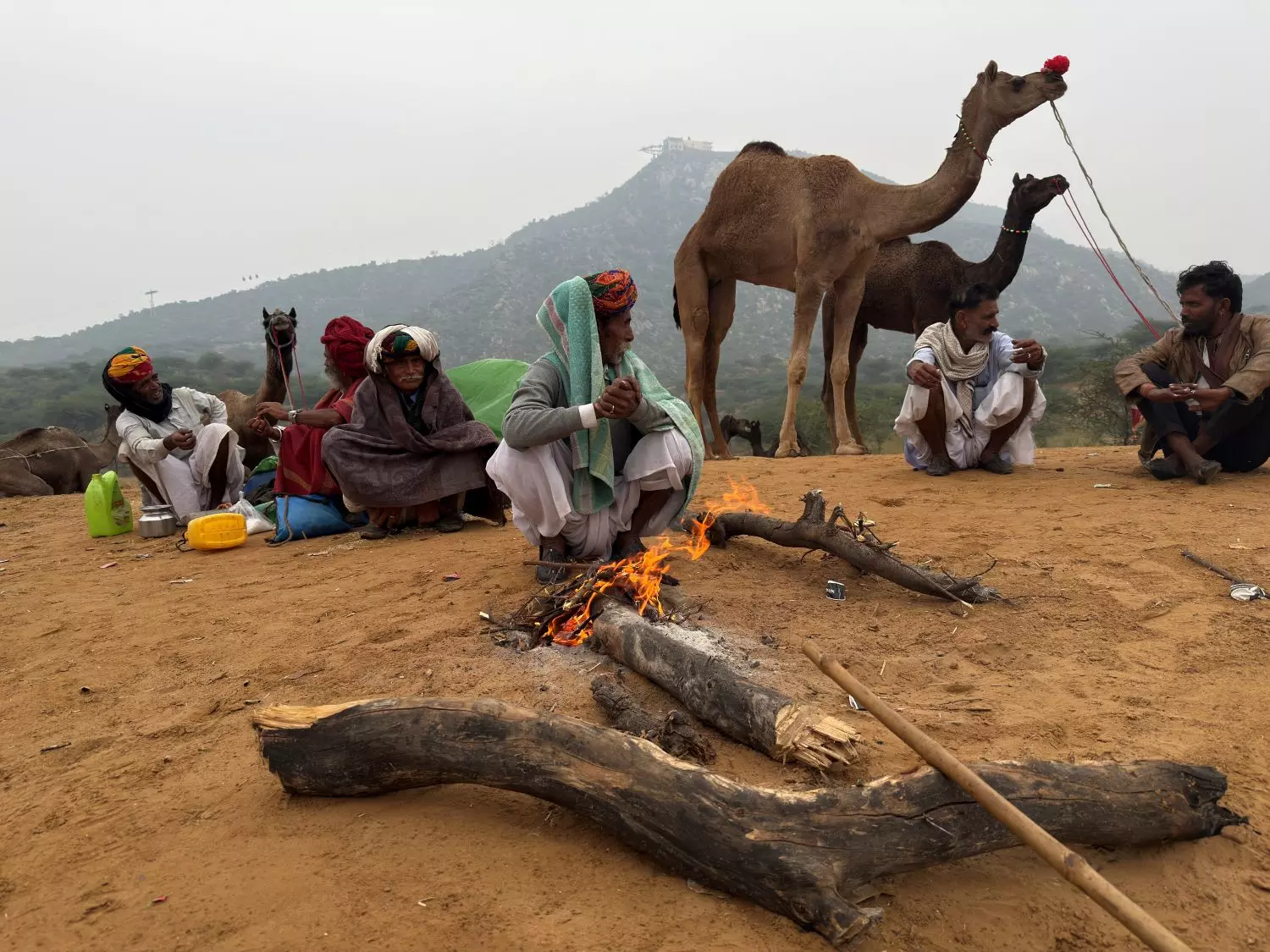 Camel breeders and traders huddle around a fire, awaiting business, in Pushkar. Photo by Ajay Suri