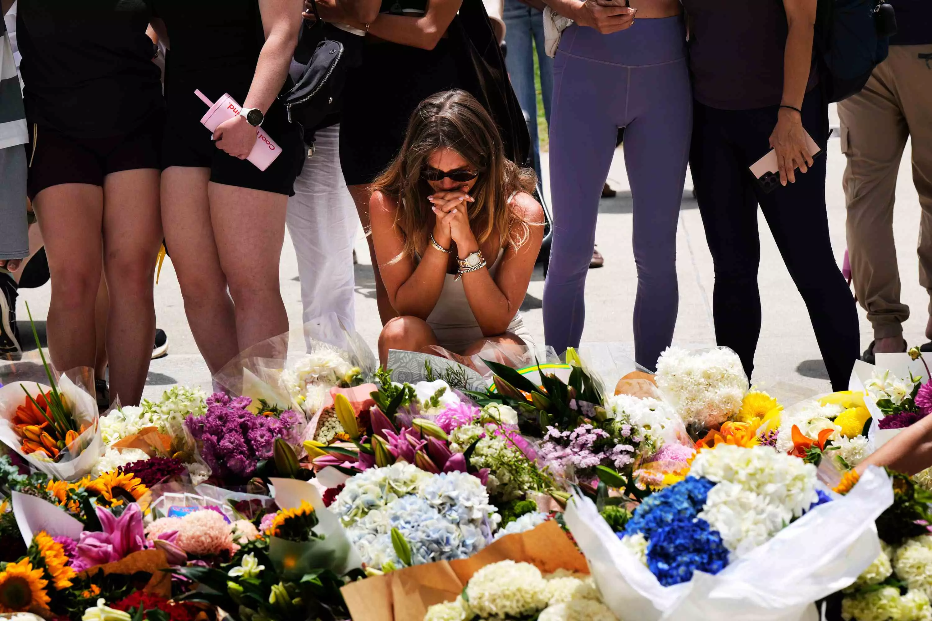 A woman kneels and prays at a flower memorial to shooting victims A woman kneels and prays at a flower memorial to shooting victims