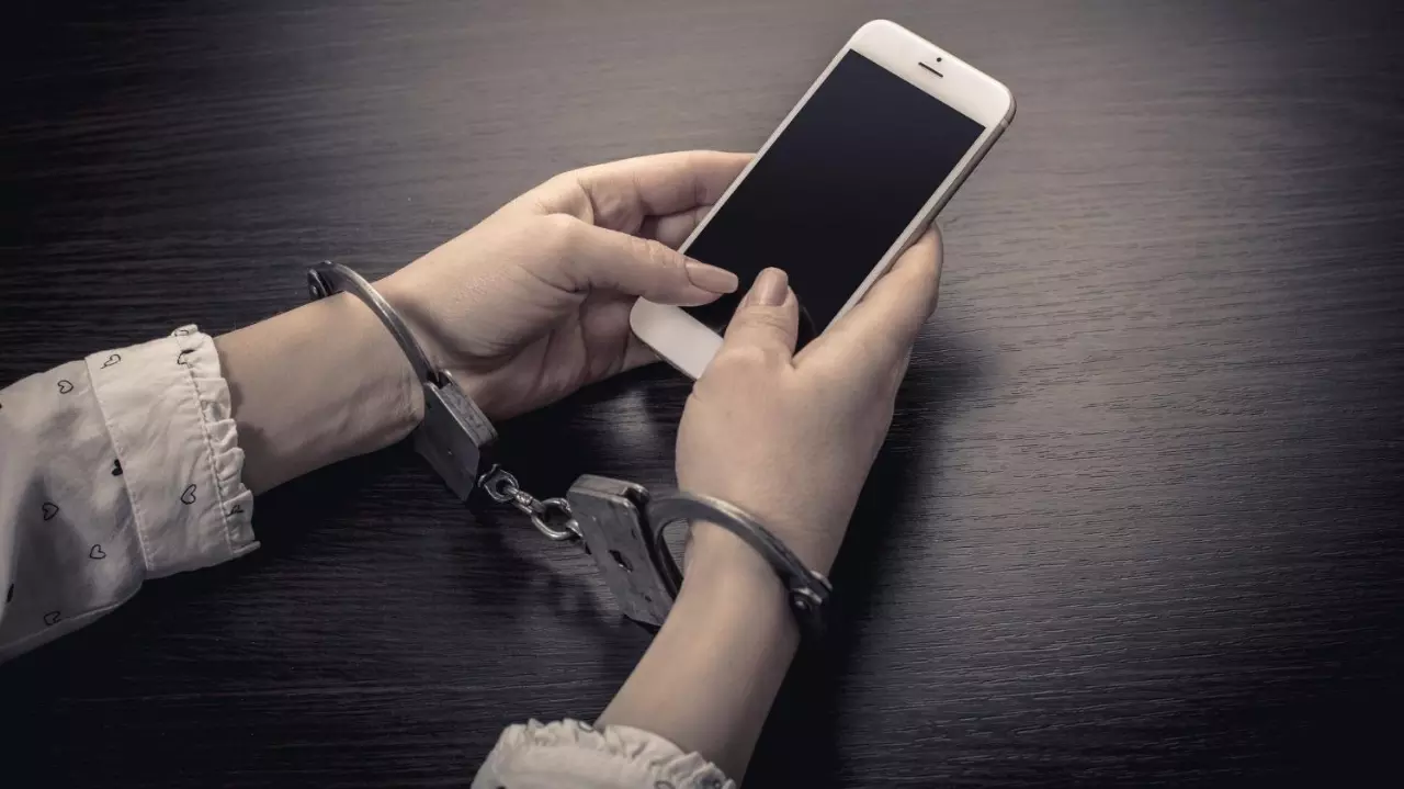 Handcuffed hands with a mobile phone stock photo