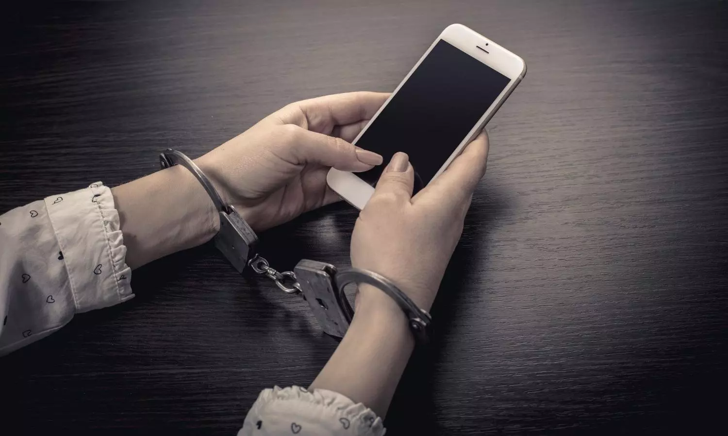 Handcuffed hands with a mobile phone stock photo Handcuffed hands with a mobile phone stock photo
