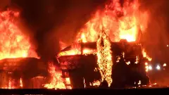 Flames and smoke billow out after a bus caught fire following a collision with a speeding truck