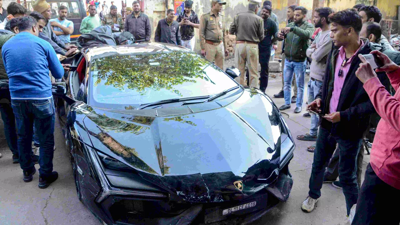 People gather around a Lamborghini car which collided with a rickshaw, injuring three people, in Kanpur