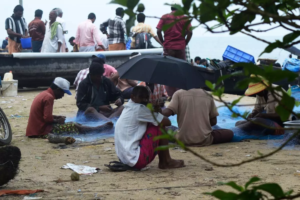 Fishermen repair nets on shore. Photo: Ima Babu