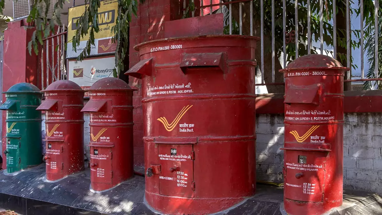 Senior citizens at a Chennai post office counter discussing savings schemes with staff.