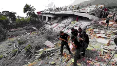 A man walks among the rubble of a building that collapsed in earthquakes the previous day in La Guaira, Venezuela
