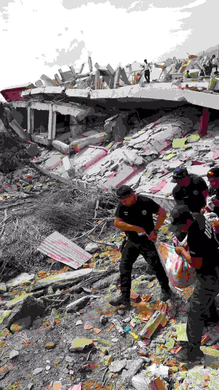 A man walks among the rubble of a building that collapsed in earthquakes the previous day in La Guaira, Venezuela