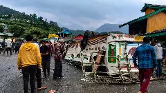 People gather after a private bus overturned and plunged onto a lower road, in Chamba district, Himachal Pradesh
