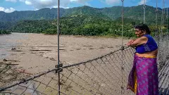 A woman looks at the indundated area after flash floods, in the Devghat area, Nepal, Thursday, Aug. 27, 2026